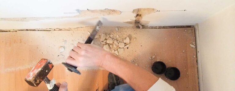 Ein Handwerker bereitet im Altbau die Wände zum Verlegen neuer Elektroleitungen und zum Setzen neuer Steckdosen vor.